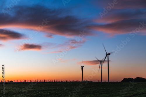 Silhouette of three modern windmills under a blueish sunset on the outskirts of Kiyú, San José, Uruguay
