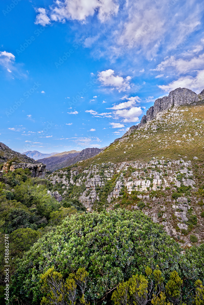 Copy space with mountain landscape against a cloudy blue sky background in Cape Town. Beautiful and calm scenic of lush green plants and trees around a majestic rocky valley on a sunny day in nature Copy space with mountain landscape against a cloudy blue sky background in Cape Town. Beautiful and calm scenic of lush green plants and trees around a majestic rocky valley on a sunny day in nature