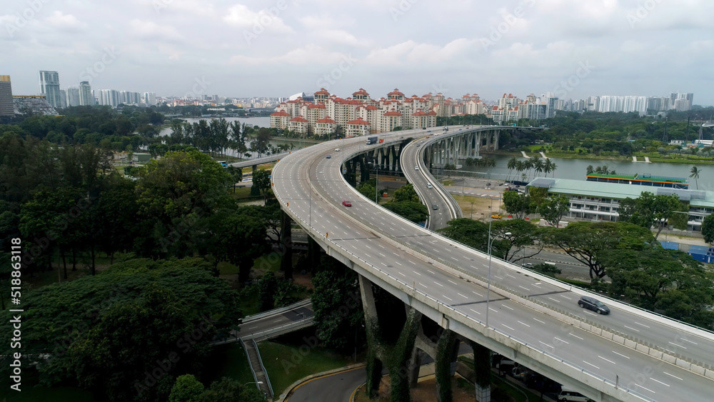 Panoramic aerial view of river bridge in the city with trees in parks. Shot. Aearial view of the bridge with cars crossing a beautiful river and modern cityscape.