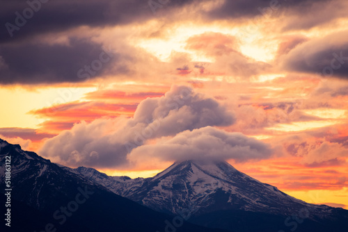 montañas nevadas con cielo rojizo de atardecer y nubes cúmulos de color rojos y amarillos 