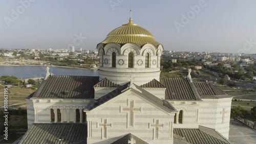 View of the big white church with golden domes in front of beautiful river, spring Vologda, Russia. Shot. Beautiful aerial from the bird's eye view for the big church on the river bank. photo