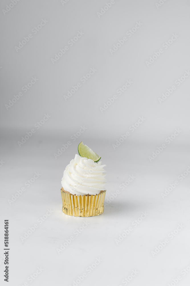 Vanilla cupcake with white buttercream and lime wedge, gold cupcake liners, lime cupcake Vanilla cupcake with white buttercream and lime wedge, gold cupcake liners, lime cupcake
