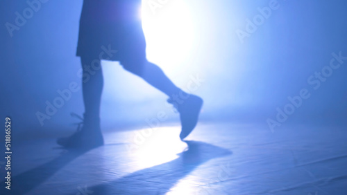 Bottom view of fighter training in the gym with smoke and light background. Silhouette of strong male boxer on dark background. Close up of athlete or sportsman moving fast while training
