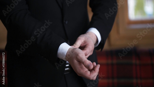 Man buttoning on a black jacket. Wedding details - elegant groom dressed wedding tuxedo costume is waiting for the bride. businessman buttoning jacket, getting dressed. Groom buttons jacket