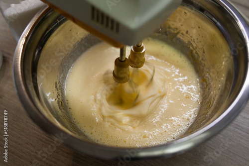 Beating with electric mixer sugar and eggs in a bowl on the wood table. Step for making muffins, pie, biscuit. baking process step by step. prepare cake for Mother's day.