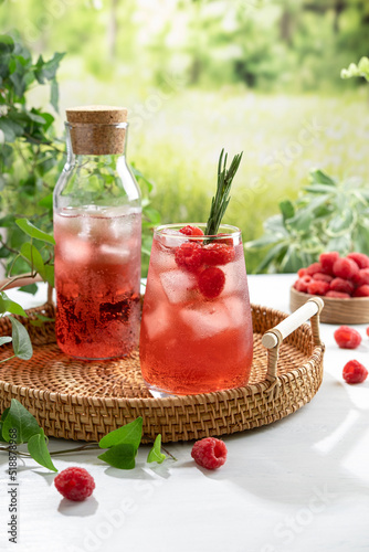 Summer refreshing non-alcoholic cocktails. Raspberry lemonade garnished with fresh rosemary. Summer raspberry beverage with sparkling water. Copy space.
