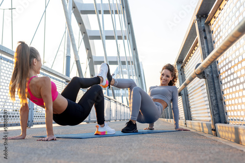 Two young woman exercise and stretch before jogging on the bridge