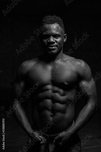 Portrait of an African American man with a naked torso in a dark studio. Muscular guy.