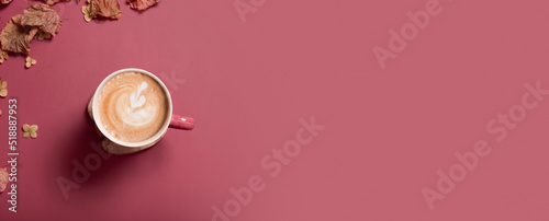 Autumn flat lay banner with dry leaves and coffee latte cup on dark pink color background. Creative autumn, thanksgiving, fall, halloween concept. Top view, copy space