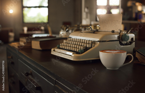 Focus on white coffee cup on old wooden table and blurred old typewrite, old book in office room retro style, vintage color tone