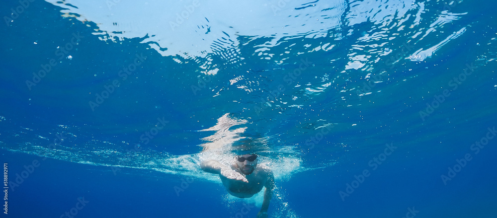 Boy swims freestyle in the open ocean.