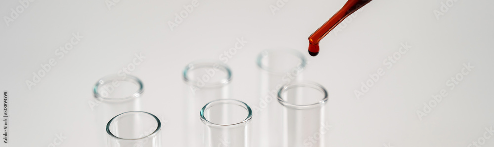 Close-up of a laboratory assistant dripping blood from a pipette into a test tube on a white background. Close-up of a laboratory assistant dripping blood from a pipette into a test tube on a white background.