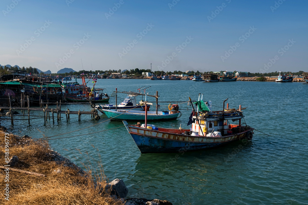 Fishing boats at fisherman dock in sea against blue sky at Cha Am