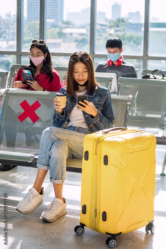 Canvas Print Asian girl using phone at airport departure waiting seat