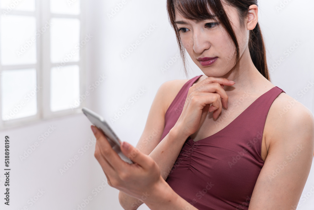 トレーニング中にスマホ操作する女性 トレーニング中にスマホ操作する女性