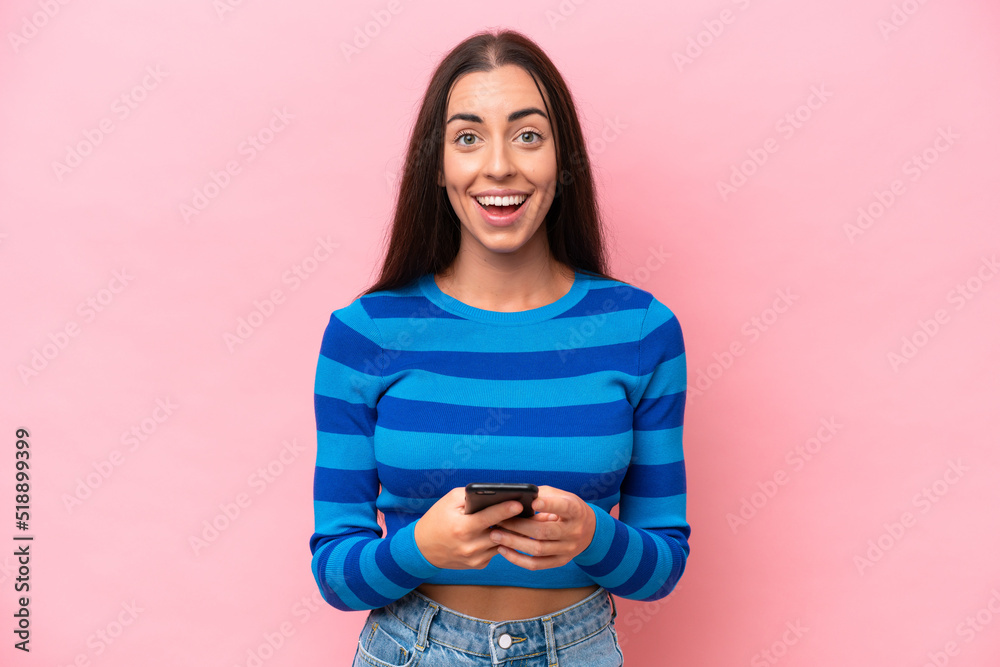 Young caucasian woman isolated on pink background surprised and sending a message Young caucasian woman isolated on pink background surprised and sending a message