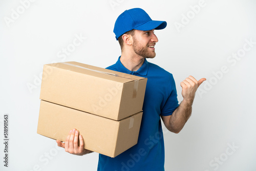 Delivery man over isolated white background pointing to the side to present a product © luismolinero