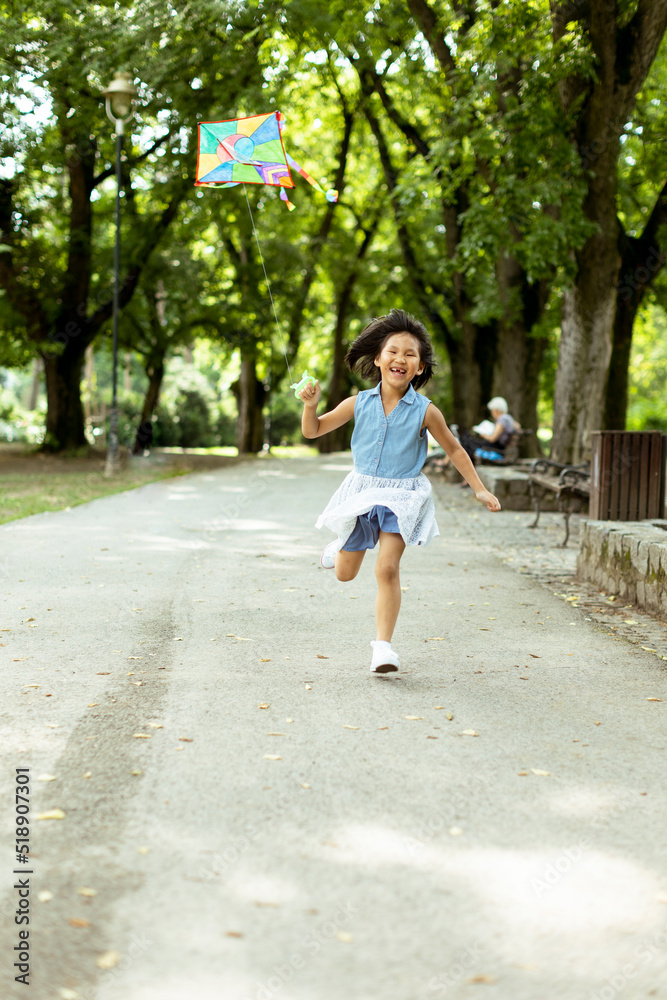 Little Asian girl running happily with a kite in the park Little Asian girl running happily with a kite in the park