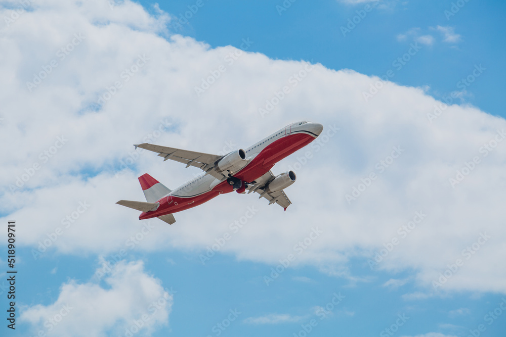 Passenger plane of white-red color flies in the blue sky with white clouds, air transportation concept, population evacuation Passenger plane of white-red color flies in the blue sky with white clouds, air transportation concept, population evacuation