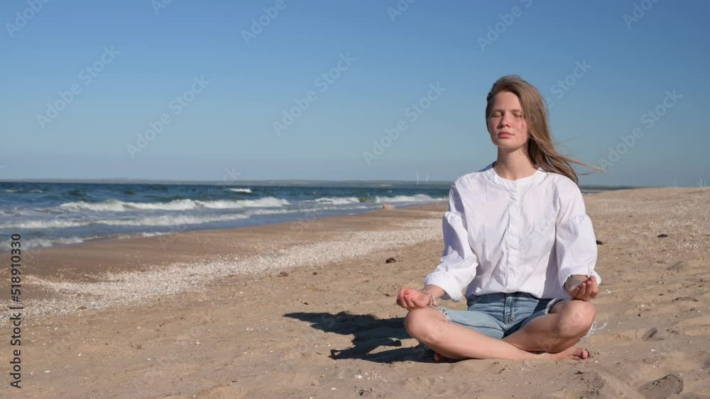 Girl meditating by the sea. Wind shakes long blond hair Girl meditating by the sea. Wind shakes long blond hair