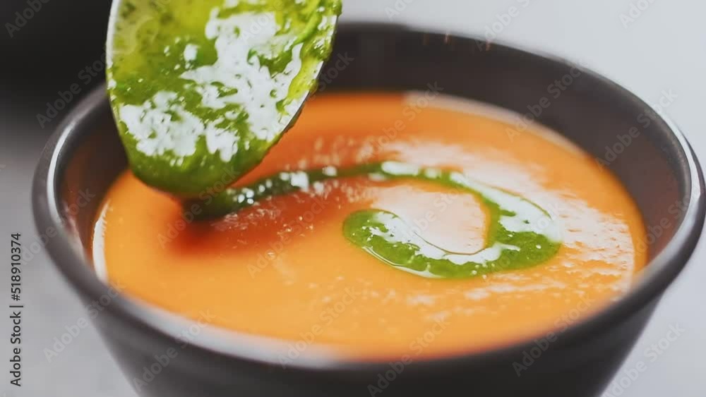 Chef adds basil olive oil on a tasty creamy tomato soup.
Chef adds basil olive oil on a tasty creamy tomato soup.