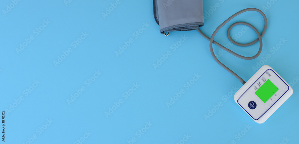 Automatic device for measuring blood pressure with heart from a tonometer cord on a blue medical background. Headache, treatment of hypertension and hypotension. Copy space. Medical concept banner. Automatic device for measuring blood pressure with heart from a tonometer cord on a blue medical background. Headache, treatment of hypertension and hypotension. Copy space. Medical concept banner.