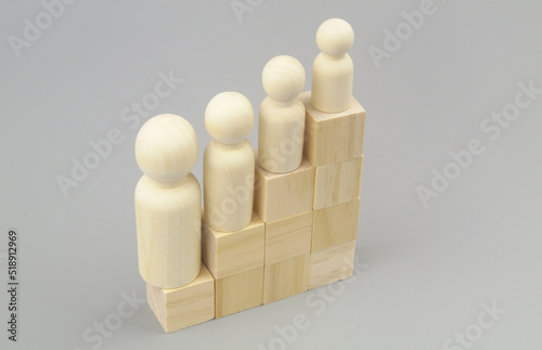 Degradation people in career and politics concept. Different wooden people figures on stair made of wooden cubes. Higher step - smaller person.