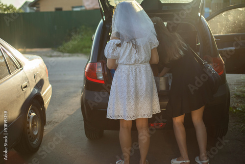 Bride is in parking lot. Bridesmaids at car dealerships. Trunk of car. Girls are getting ready for trip. © Олег Копьёв