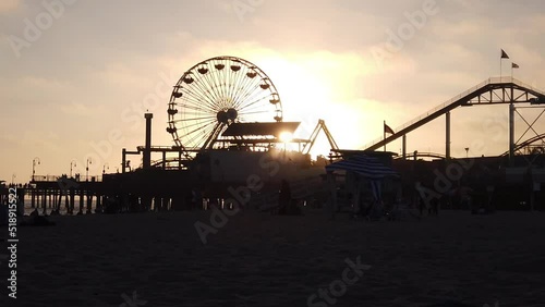 Los Angeles, California, USA, June 21, 2022: SLOW MOTION SHOT - View of Santa Monica Beach and the Pier at sunset. Santa Monica Ferris Wheel and Roller-coaster.