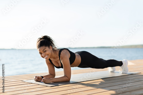 Cheerful african american woman doing workout at seaside