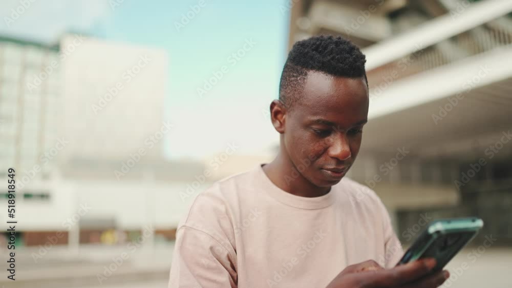 Young african student sitting outside of university, using cellphone, sending voice message
