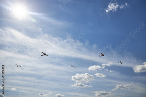 Five sports planes against the blue sky and the sun.