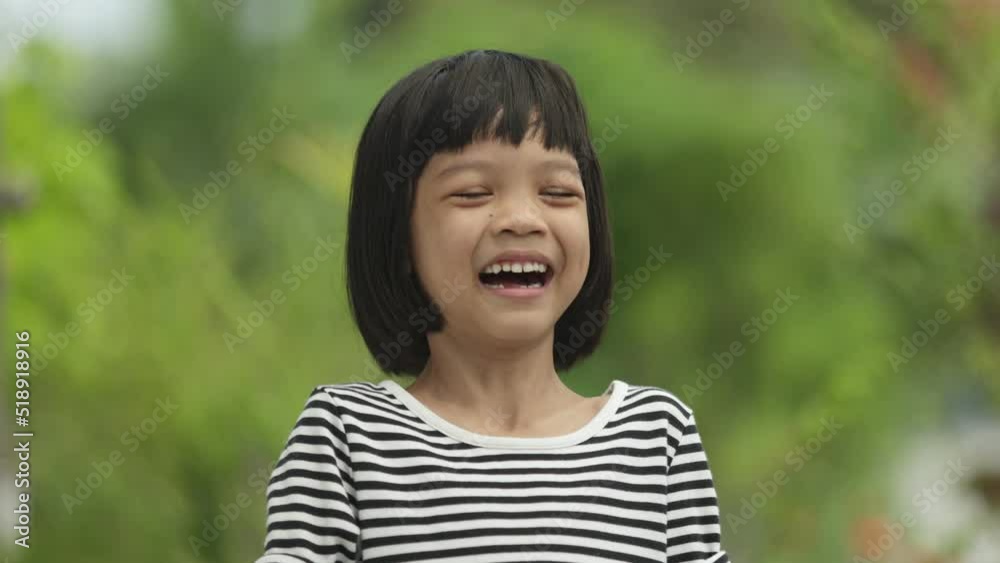 Asian Thai kid girl standing in the outdoor garden She was a child with a beautiful face.in school age She was smiling and laughing happily. She is in good health and Strong background is a green tree Asian Thai kid girl standing in the outdoor garden She was a child with a beautiful face.in school age She was smiling and laughing happily. She is in good health and Strong background is a green tree