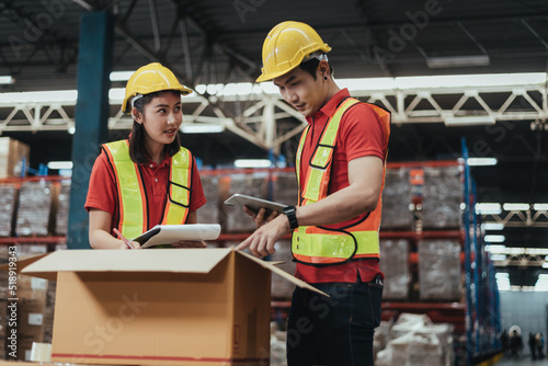 Warehouse Workers Checking Stock with digital Tablet in Logistic center. Asian workers wearing hard hat and safety vests to talking about shipment in storehouse  Working in Distribution Center.