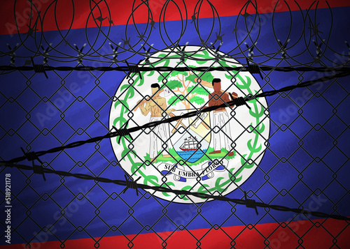 Belize flag behind barbed wire and metal fence