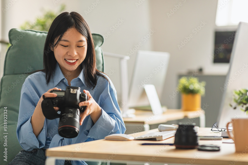 Cheerful Japanese Lady Photographer Holding Photocamera At Workplace Indoor Cheerful Japanese Lady Photographer Holding Photocamera At Workplace Indoor