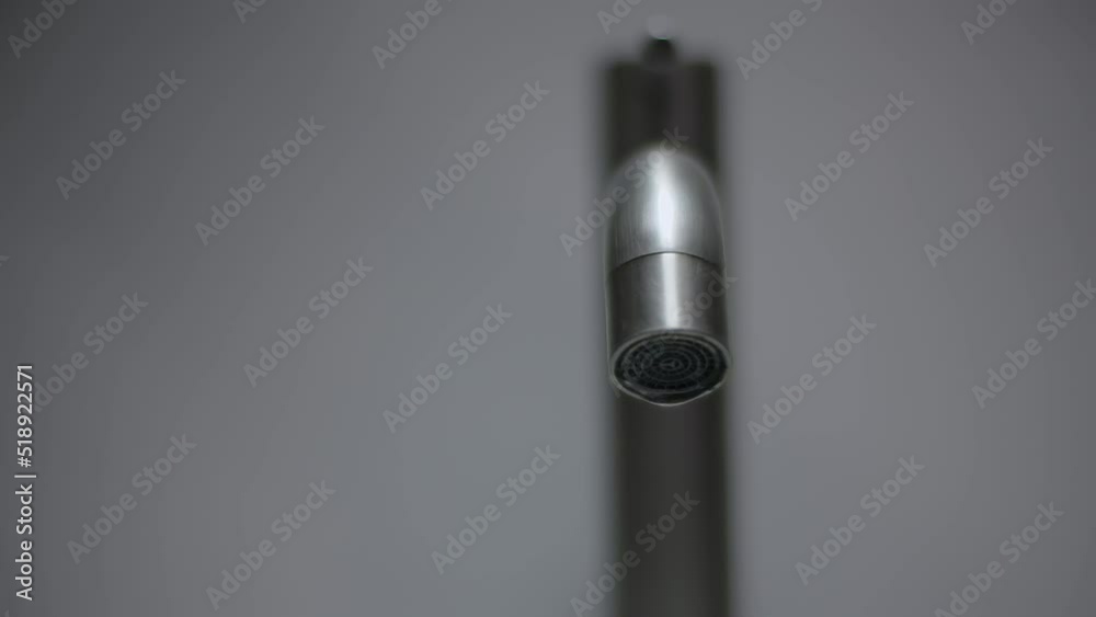 Close-up of a metal water faucet on a white background isolated. Drop falling in slow motion 200 fps Close-up of a metal water faucet on a white background isolated. Drop falling in slow motion 200 fps