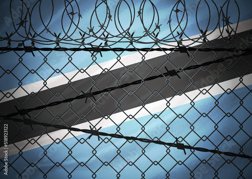 Botswana flag behind barbed wire and metal fence