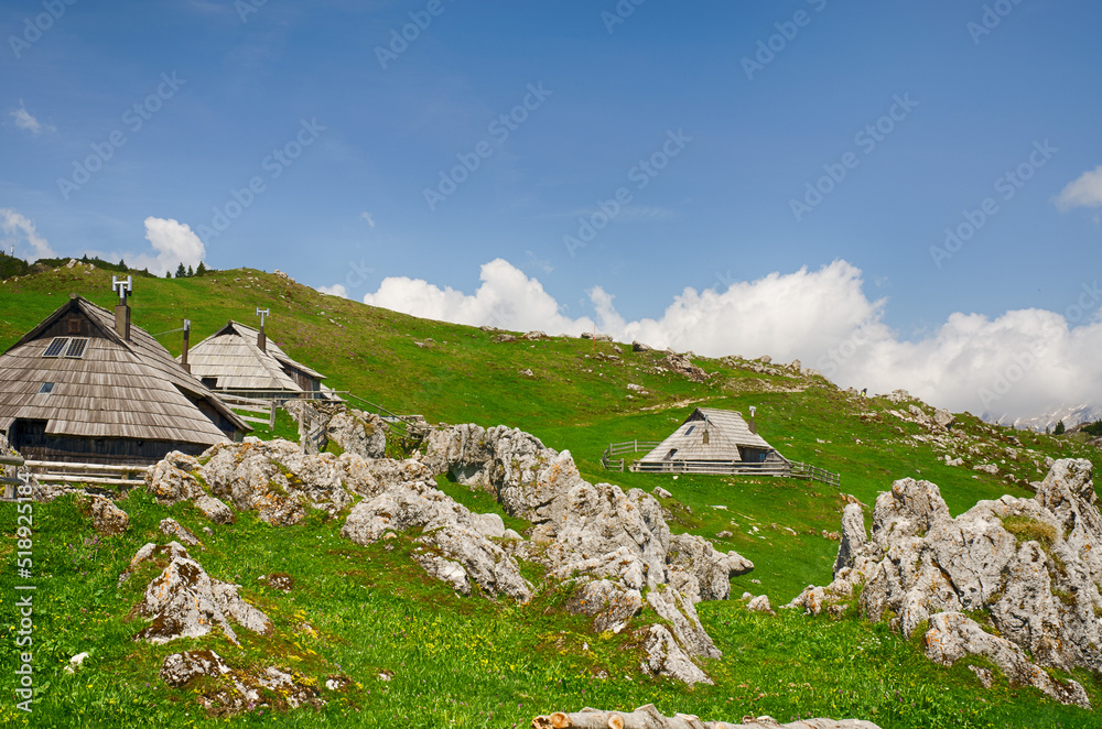 Velika Planina or Big Pasture Plateau in the Kamnik Alps, Slovenia. Mountain cottage hut or house on green hill. Alpine meadow landscape. Eco farming Velika Planina or Big Pasture Plateau in the Kamnik Alps, Slovenia. Mountain cottage hut or house on green hill. Alpine meadow landscape. Eco farming