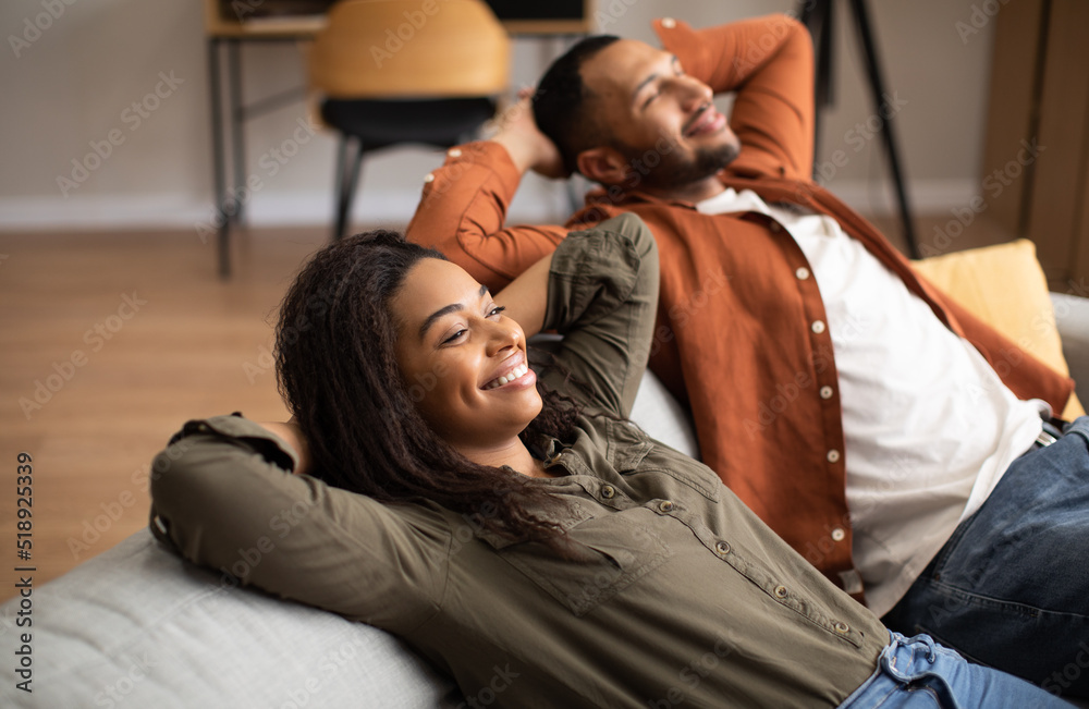 Obraz premium Happy African American Couple Relaxing Sitting On Sofa At Home