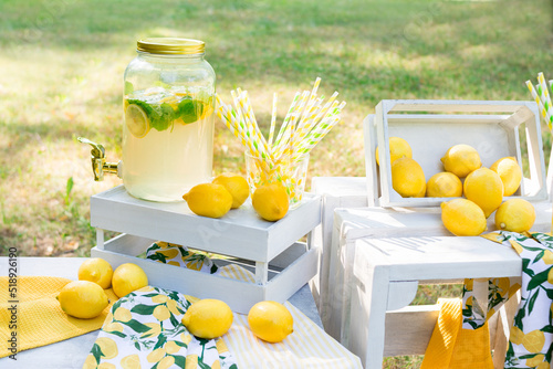 Lemonade in the park with mint and lemons. Juicy lemons in wooden boxes. Cold homemade summer drink.