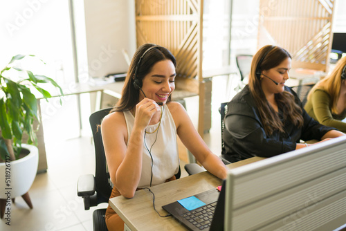 Happy customer support agent smiling while talking with a client photo