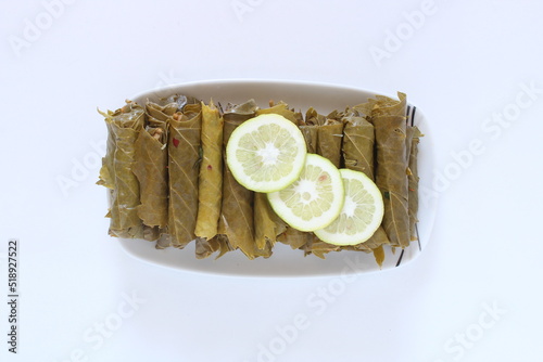 Turkish cuisine food Yaprak Sarma (Wrap stuffed) with lemon slices. Grape leaves stuffed with rice isolated on white. Top view, close up of traditional Turkish or Greek cuisine culture food Sarma.