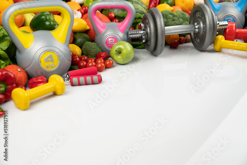 Fitness concept. Healthy nutrition: fruits and vegetables. Equipment for fitness exercises: weighing machine and dumbells. White background.