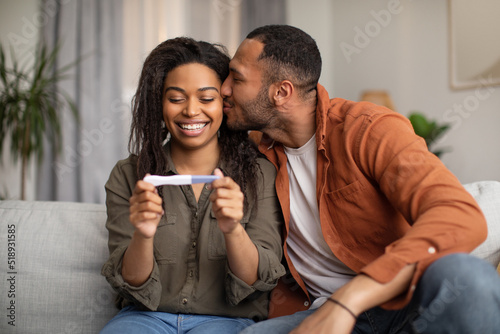 Happy African American Couple Holding Positive Pregnancy Test At Home photo
