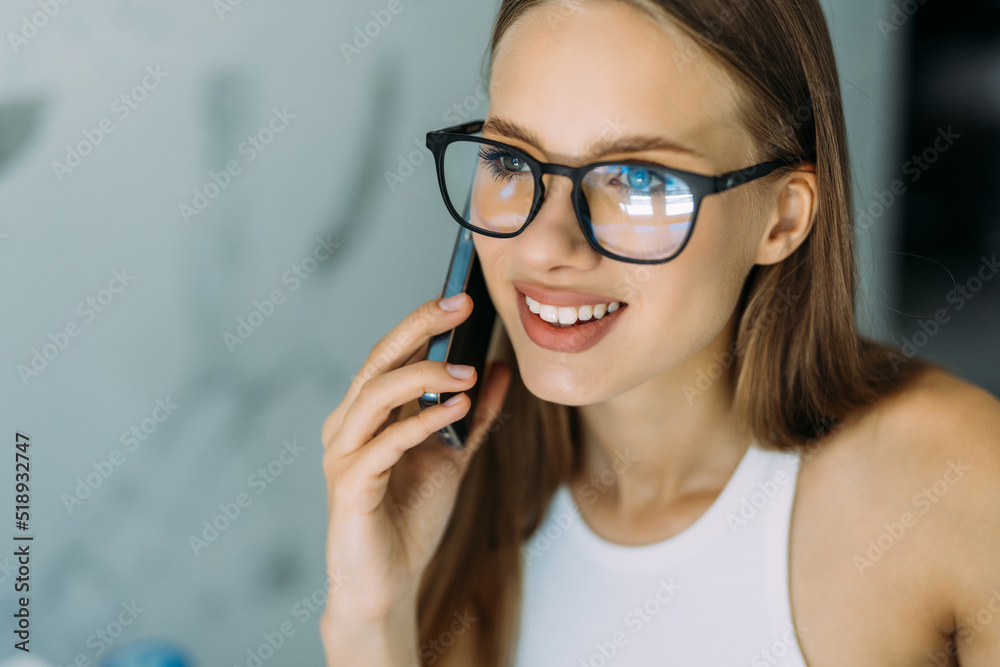 Cheerful young woman talking on the phone in the kitchen Cheerful young woman talking on the phone in the kitchen