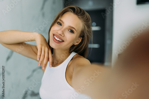 Self portrait of charming woman in shirt shooting selfie on front camera with two hands having video call with her lover