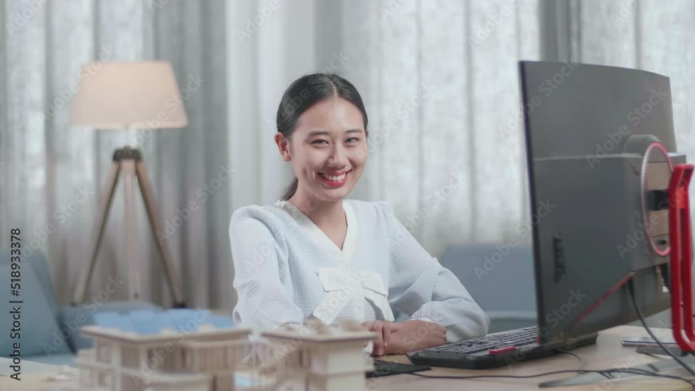 Asian Woman Engineer With The House Model Smiling To The Camera While Working On A Desktop At Home
Asian Woman Engineer With The House Model Smiling To The Camera While Working On A Desktop At Home