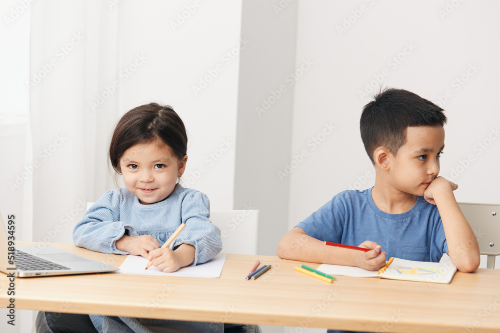 small children sit at the table during class and look at each other small children sit at the table during class and look at each other