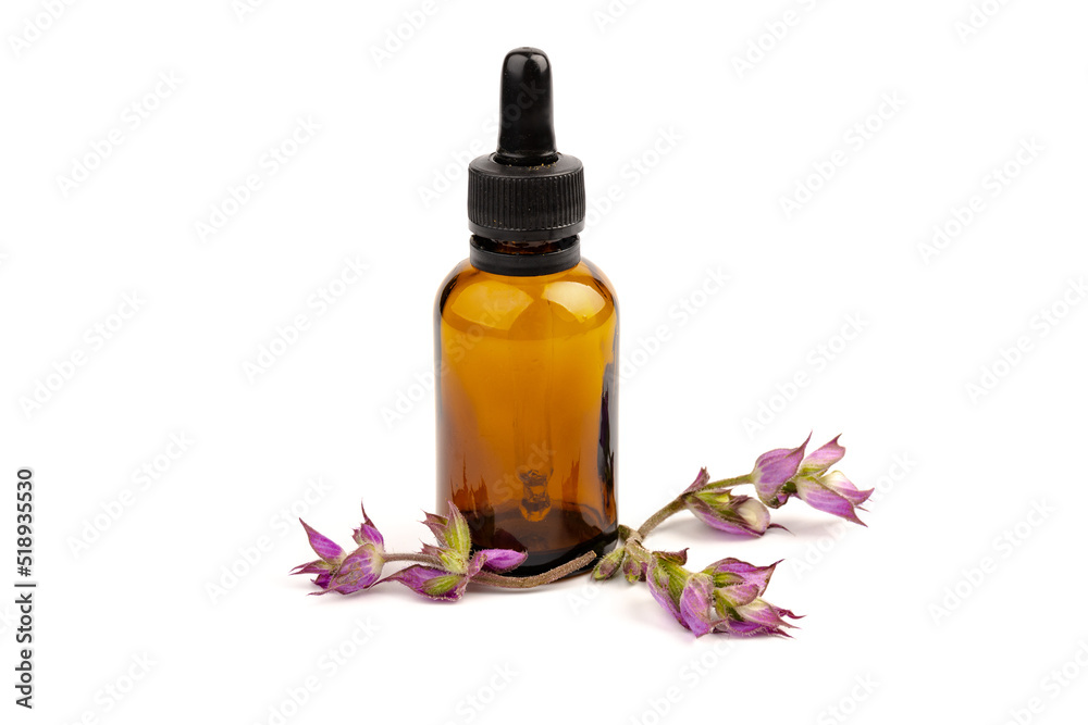 A bottle of essential oil with fresh blooming clary sage twigs on white background. A bottle of essential oil with fresh blooming clary sage twigs on white background.